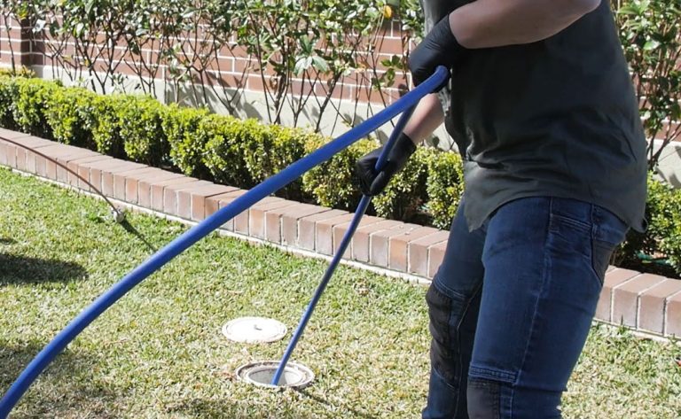 a relining company employee navigating an outdoor drain with a long pipe tool