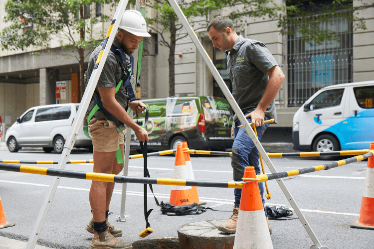 Relining employees fixing a drain hole on the side of the road