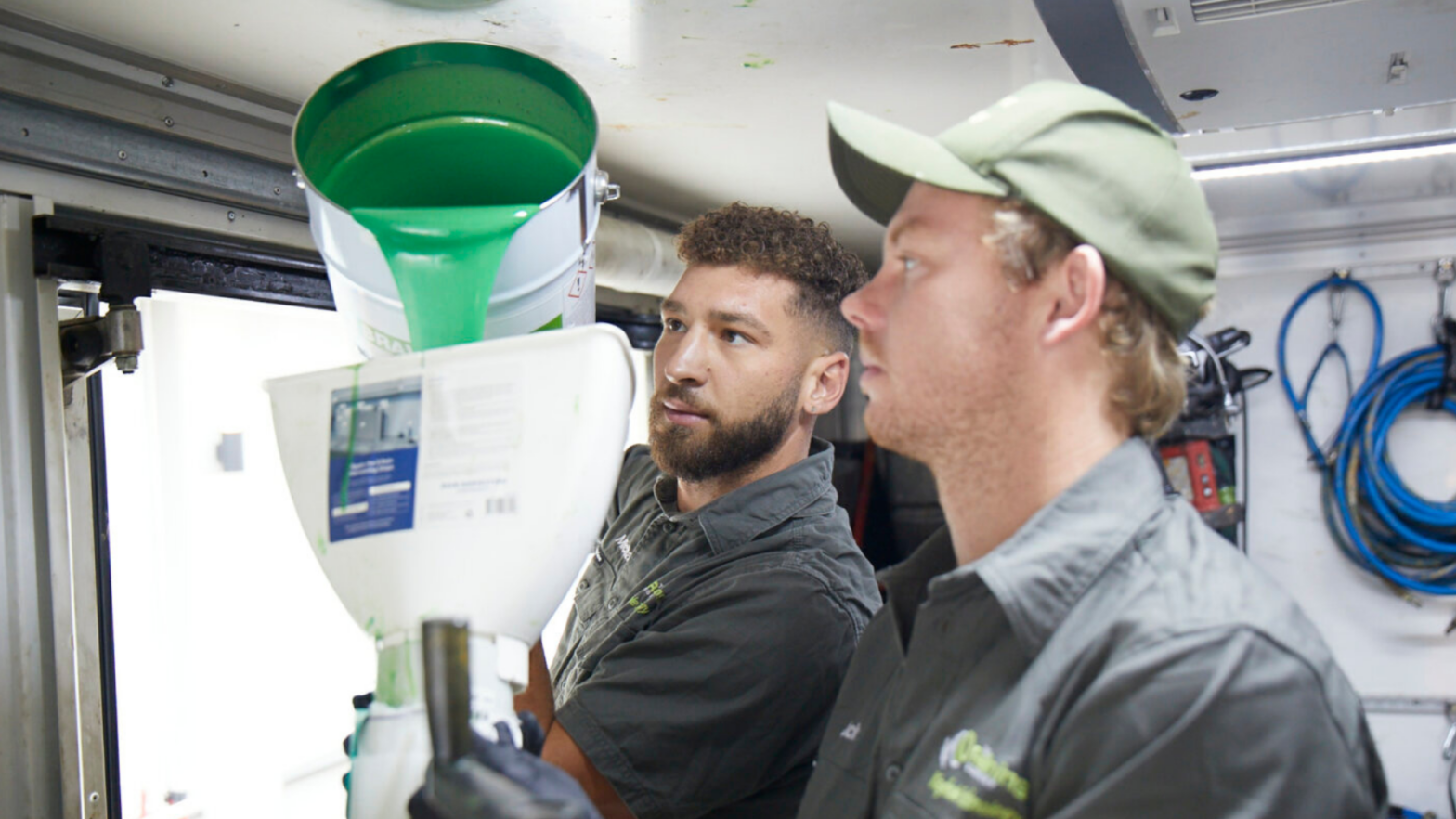 Workers pouring a liquid substance into another container