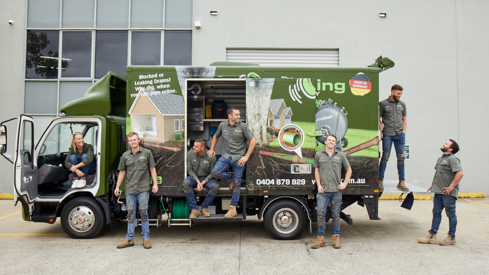 Pipe Relining Employees standing outside the Relining Truck looking happy